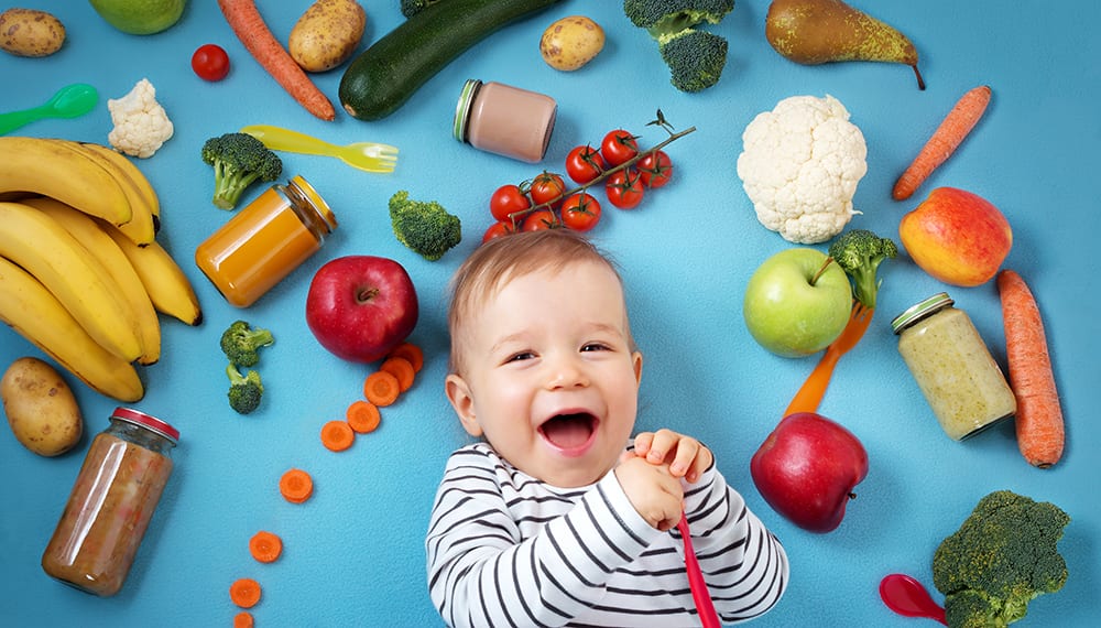 Smiling baby surrounded by nutritious food